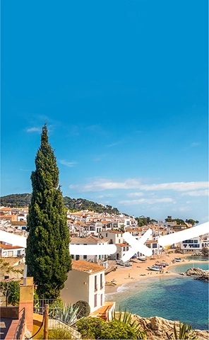 View of the coastline and nearby town in Fang Aventura, Girona — featuring rugged cliffs, blue waters, and scenic urban surroundings.