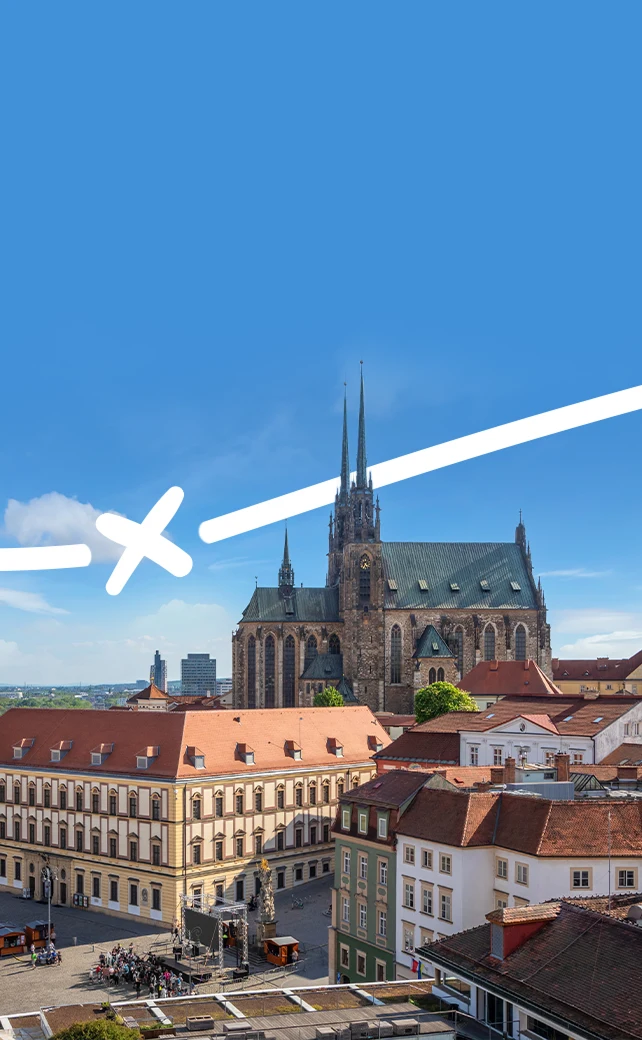 An aerial view of the historic city of Brno, Czech Republic, featuring the Cathedral of St. Peter and Paul with its prominent twin neo-Gothic spires.